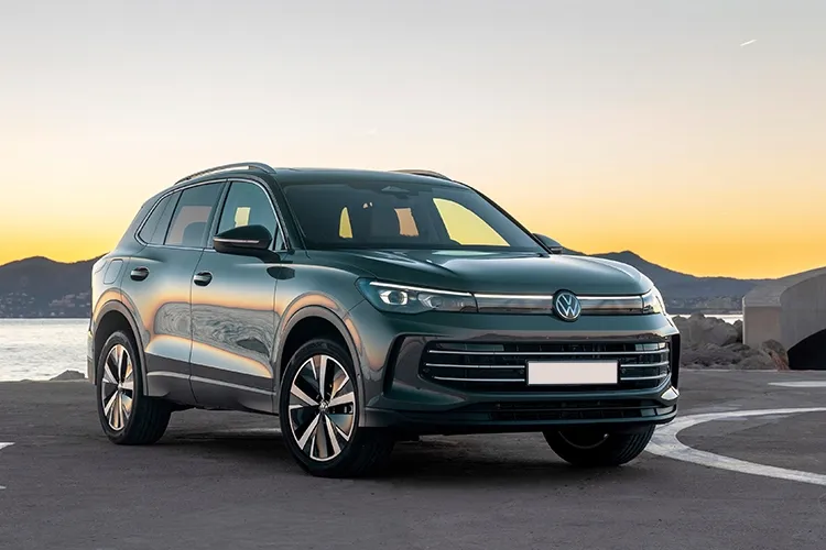 A grey Volkswagen Tiguan driving along a scenic road.
